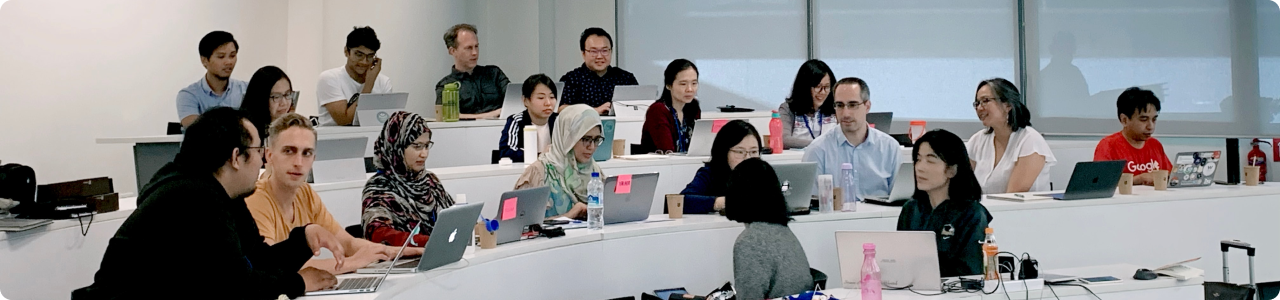 A diverse group of students with laptops in a classroom.