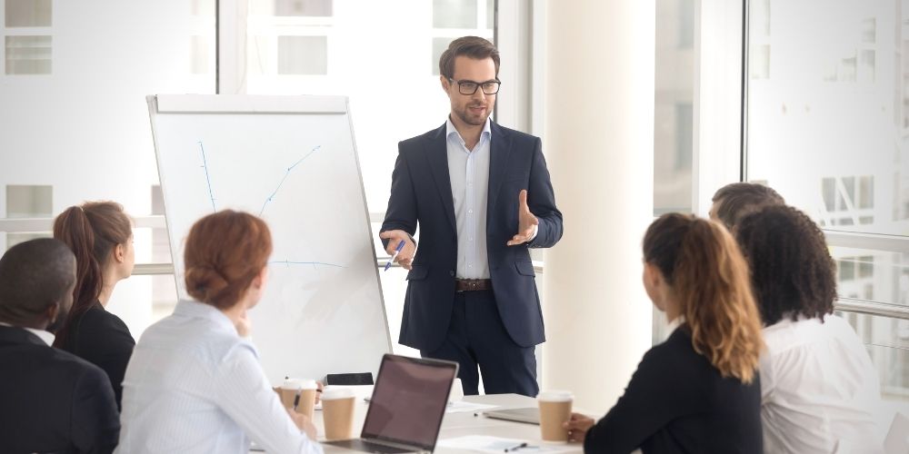 A man in a suit presenting to a group of people.