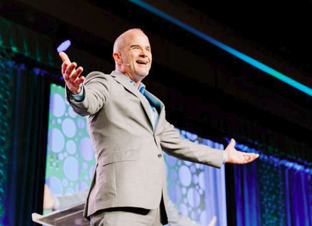 Jeff Shore stands on stage with his arms open