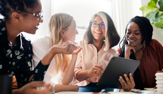 Group of four women sitting in an office laughing