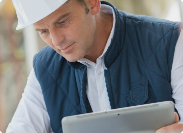 An engineer in a hardhat holding a tablet.