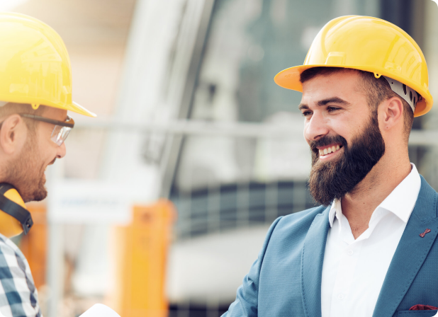 A man in a hard hat smiling at a construction worker.