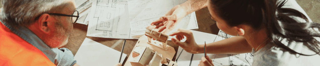 a man and a woman drawing out blueprints for their construction project