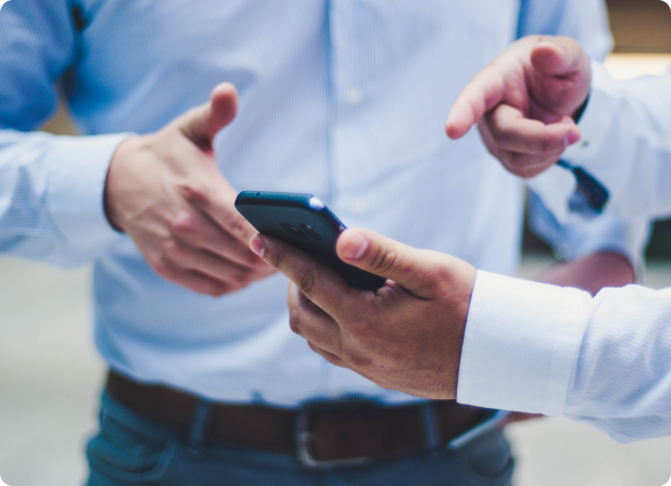 A man pointing at a phone to another man.